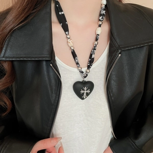 Close-up of heart pendant with silver cross on leopard print necklace and gothic chain