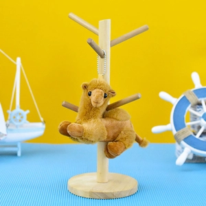 Detailed close-up view of a cute plush camel keychain hanging on a decorative wooden stand