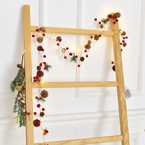 Christmas LED string lights with pine cones and red berries on a wooden ladder