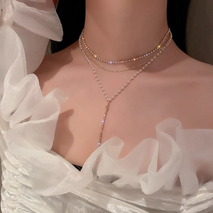 Detail of layered gold necklace with rhinestones and faux pearls on model's neck