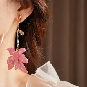 Close-up of vintage golden branch earrings with pink enamel flower on a model