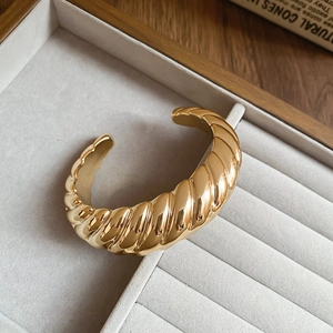 Detailed view of a gold croissant twisted cuff bracelet in a jewelry box