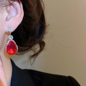 Close-up of elegant red teardrop zircon earrings with clear accents on a model