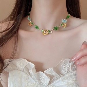 Detail of beaded necklace with sunflower charms and blue flower accents on model