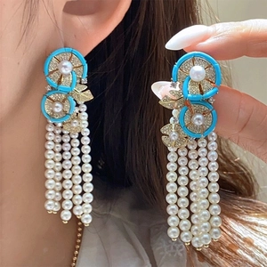 Detailed view of vintage gold earrings with teal enamel, pearls and dangling fringe