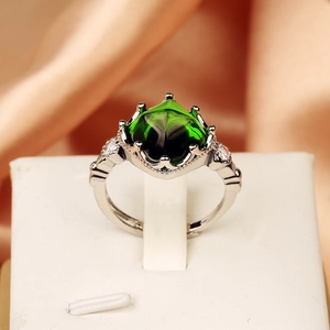 Macro shot of sugarloaf cut green gemstone ring with side stones on silver band
