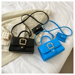 Flat lay of retro candy color crossbody square bags in black and royal blue with gold buckles