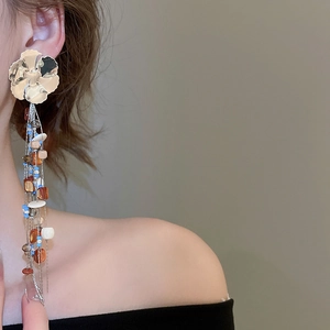 Detail of bohemian long tassel earrings with colorful beads and gold flower stud on model