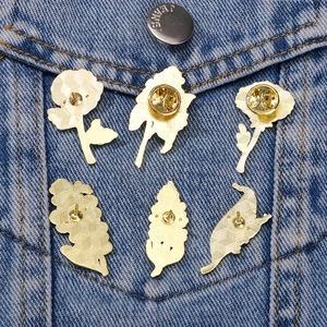 Set of six floral enamel pins with butterfly clasps on blue denim jacket pocket