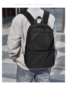 Close-up of a black nylon business backpack on a model in a modern urban outdoor setting