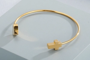 Detailed shot of golden stainless steel open bangle with cross and heart ends