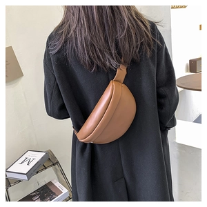 Brown semi-circle leather chest bag on black coat showing stylish crossbody fit