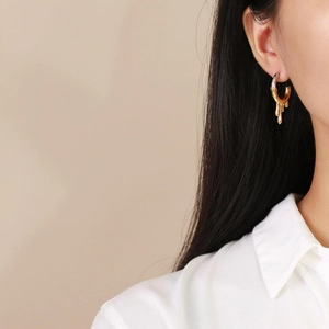 Detail of two-tone irregular liquid lava earrings worn by a model in warm light