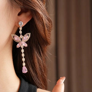 Elegant gold butterfly tassel earrings with pink and clear crystals worn by model