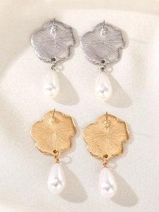 Detailed shot of flower-shaped earrings with metallic texture and drop pearl pendants