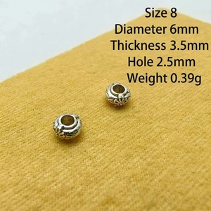 Macro detail of retro Tibetan silver spacer beads with embossed floral patterns and dimensions