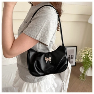 Close-up of black pleated underarm bag with silver metal butterfly decoration