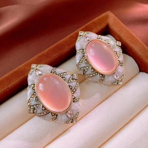 Detailed macro view of vintage rhinestone earrings with pink opal in a velvet box