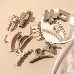 Collection of matte hair claws in various earth-tone geometric shapes on satin fabric