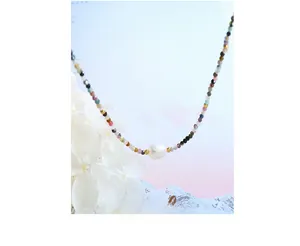 Macro detail of colorful natural gemstone beads and baroque pearl necklace with gold accents