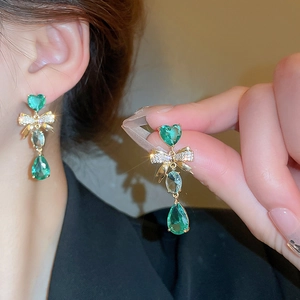 Vintage emerald green bow heart drop earrings in gold setting worn by model