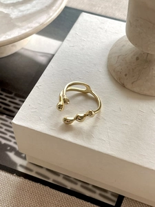 Detailed view of an irregular gold-tone adjustable ring on a white gift box