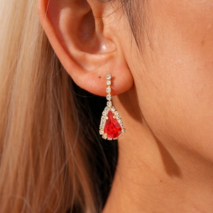 Detail view of water drop ruby red crystal earring with gold plating on model