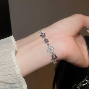 Detailed shot of silver bracelet with purple zircon flowers and hollow clover charms