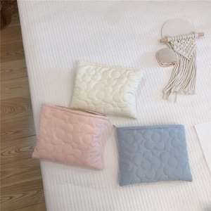 Close-up of quilted floral texture on soft puffer cosmetic bags in three pastel colors
