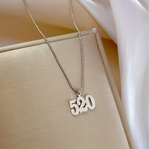 Macro shot of silver 520 pendant necklace on silk fabric inside a golden gift box