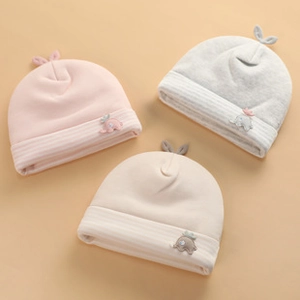 Detail showing pink, gray and beige cotton baby hats with elephant patches and small ears
