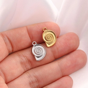Macro shot of 18K gold and silver conch shell pendants held in palm for DIY jewelry making