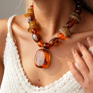 Detail of bohemian acrylic amber-style beaded necklace with large oval resin pendant