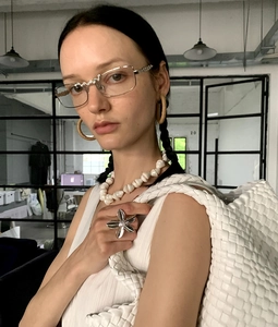 Detail of silver flower ring with pearl center worn by model with woven white tote bag
