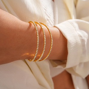 Close-up of elegant gold triple-layered bangle set with zircon inlay on woman wrist