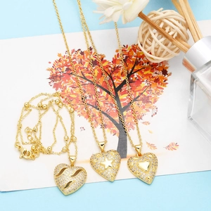 Detailed view of gold heart necklaces with zircon inlay on a blue decorative card