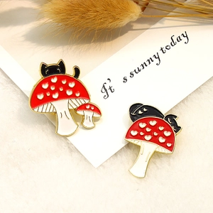 Cute black cat hiding behind red heart mushroom enamel pins in a two-piece set