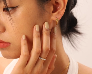 Gros plan sur des créoles torsadées dorées et une bague d'éternité sertie de zircons