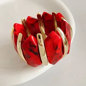 Bracelet manchette irrégulier en acrylique marbré rouge et métal doré sur plateau