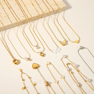 Colliers dorés et argentés avec pendentifs cœur et papillon sur pierre beige