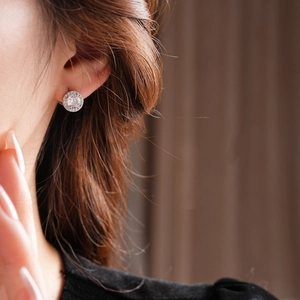 Primo piano di un orecchino in argento e zirconi con design a cerchio indossato da una modella