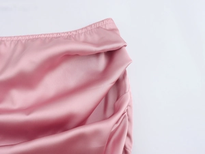 Gros plan détaillé sur la texture du satin rose et le design plissé élégant de la taille
