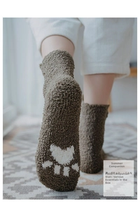 Detailed close-up of dark brown coral fleece socks with white bear paw pattern on the sole