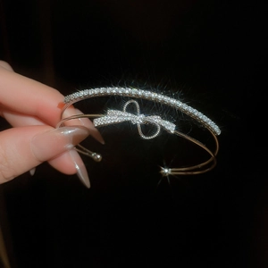Macro view of silver bow zircon bracelet with sparkling diamonds on a black background