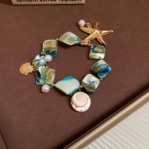 Detailed shot of starfish and shell charms with teal beads on a beach theme necklace