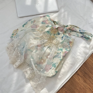 Detail of floral linen tote bag featuring delicate white lace overlay and tassel charm