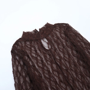 Détail d'un haut en dentelle marron foncé à col montant avec motifs ajourés