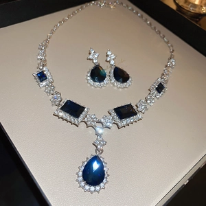 Detailed shot of teardrop blue gemstone necklace and earrings set in a beige box