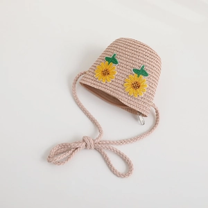 Dettaglio borsa a tracolla in paglia rosa con ricami a girasole e tracolla intrecciata