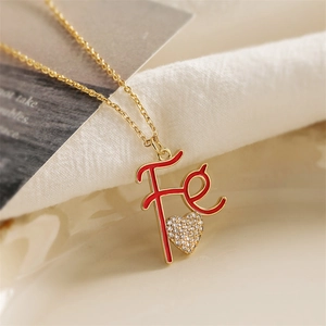 Gold letter Fe pendant necklace with red enamel and sparkling crystal heart detail